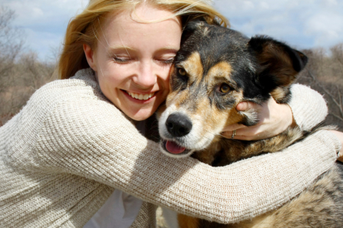 a smiling woman hugs her dog